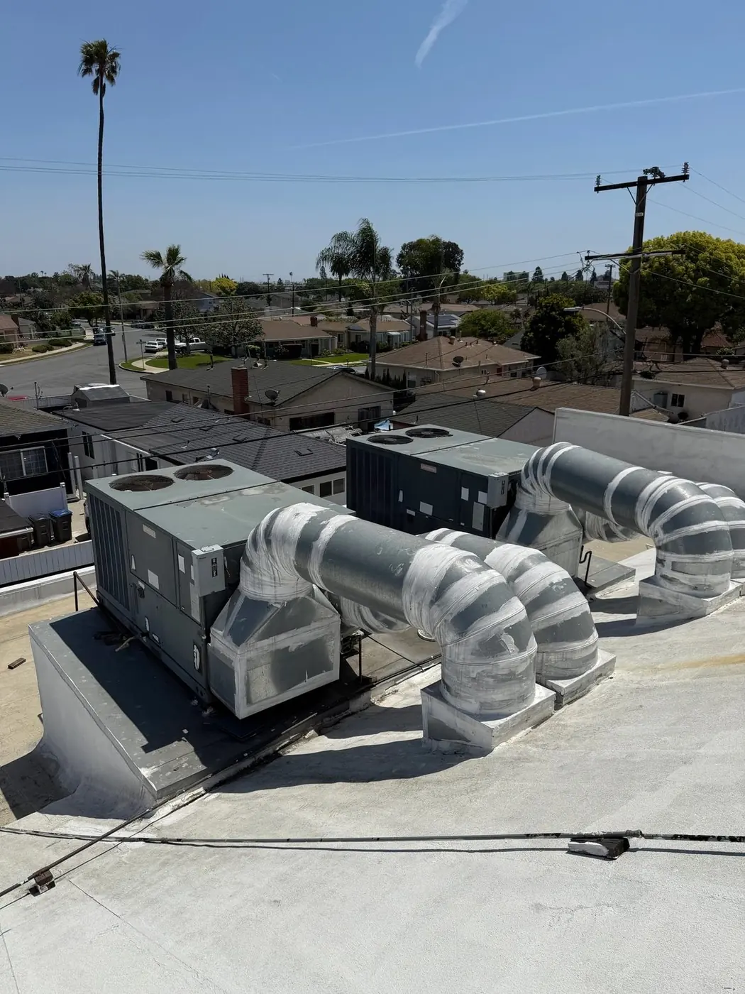 Rooftop packaged units with spiral duct runs on a light commercial building