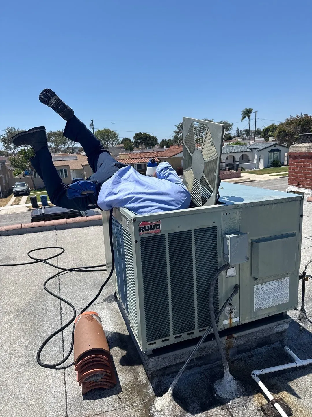 AirtekPros technician leaning into a rooftop packaged HVAC unit on a commercial building