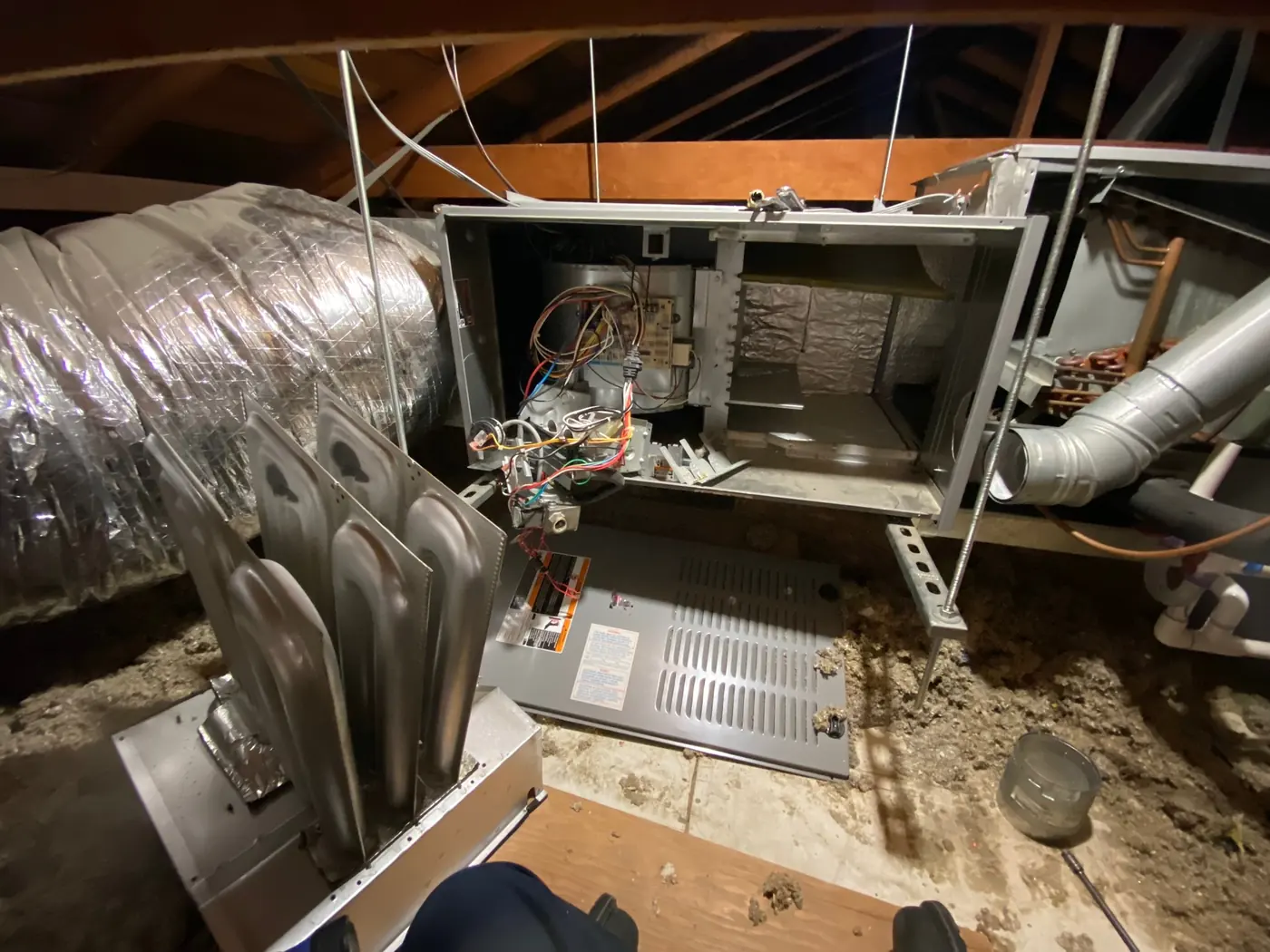 Air handler cabinet opened in an attic with insulated duct runs connected