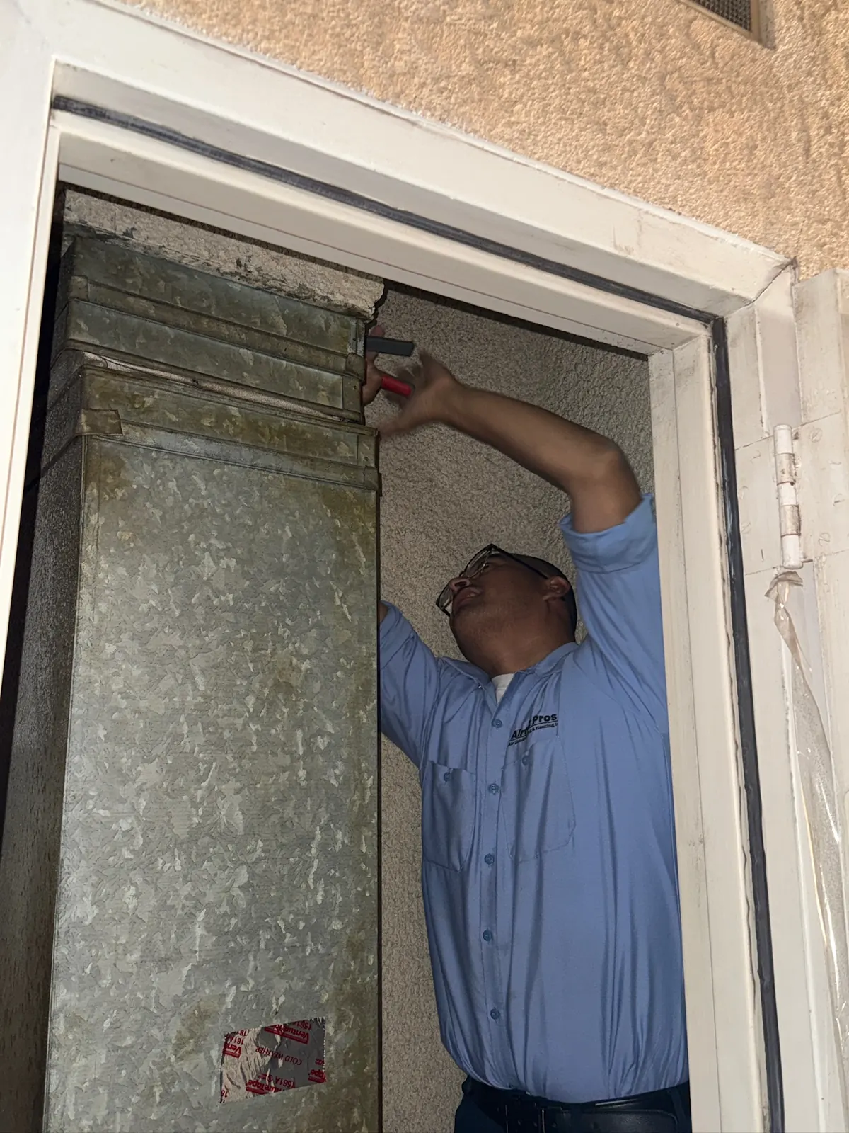 AirtekPros technician replacing a filter at a hallway return air grille