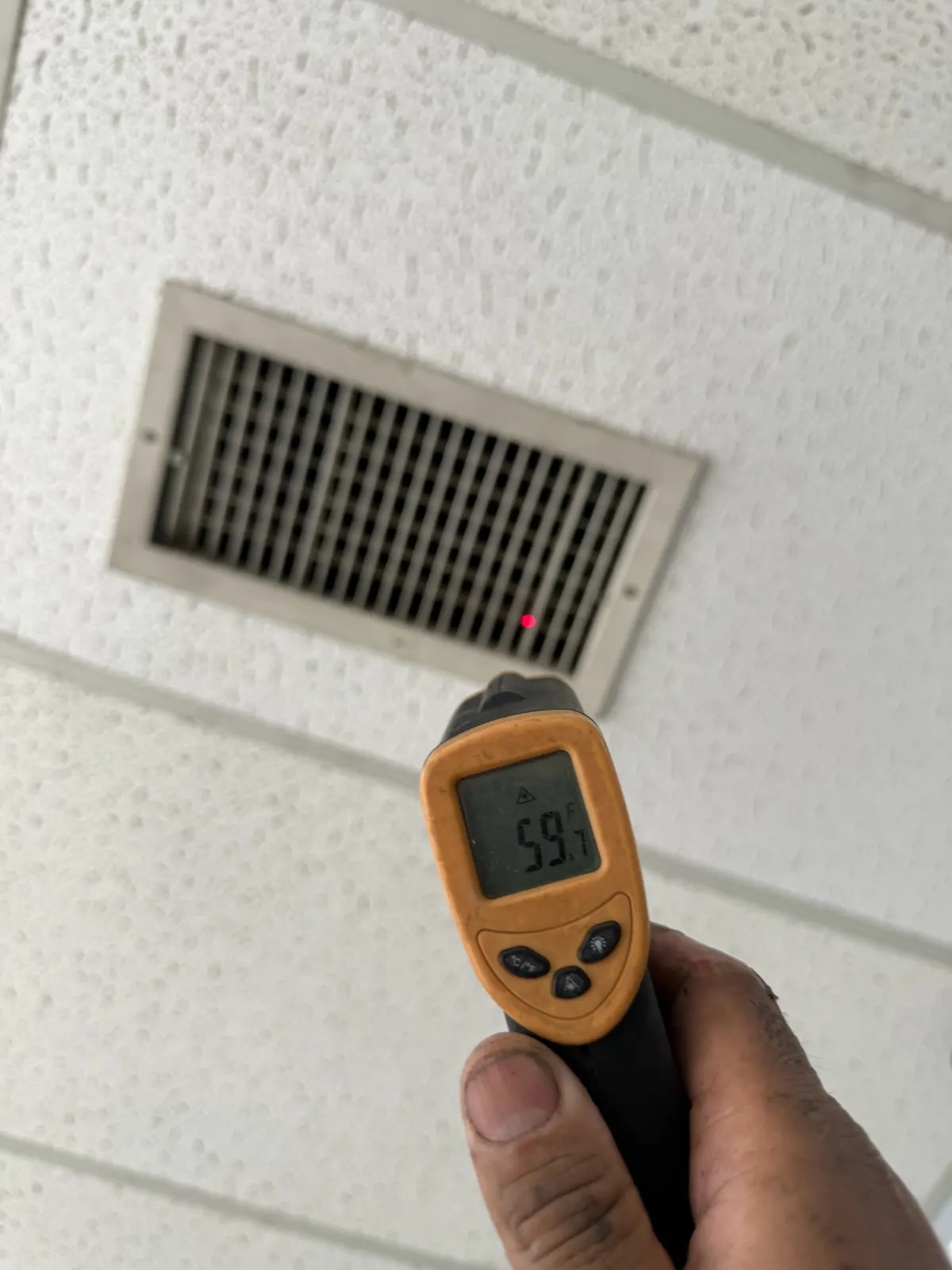 Infrared thermometer reading the supply air temperature at a ceiling register
